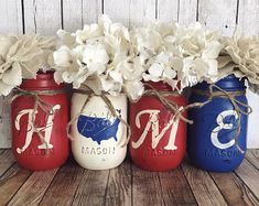 three painted mason jars with flowers in them