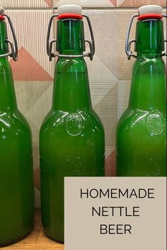 three green glass bottles sitting next to each other on a wooden table with the words homemade nettle beer