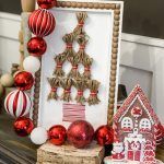 christmas decorations and ornaments are displayed on a table in front of a photo frame with an ornament