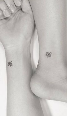 two people with matching tattoos on their feet, one is holding the other's leg