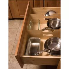 an open drawer with pots and pans in it