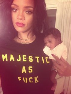 a woman holding a baby in her arms and wearing a majestic as fock t - shirt