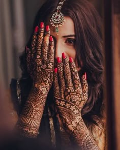 a woman holding her hands up to her face with henna on top of her