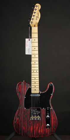 a red and black guitar sitting on top of a stand