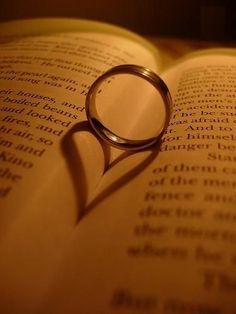 a ring casts a heart shaped shadow on an open book