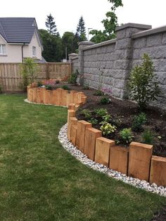 a garden with grass, rocks and flowers in the middle of it next to a brick wall