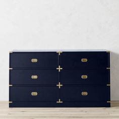 a blue dresser with gold handles in an empty room