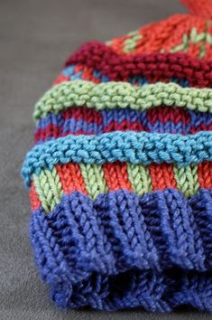 a multicolored knitted hat laying on the floor next to a pair of scissors