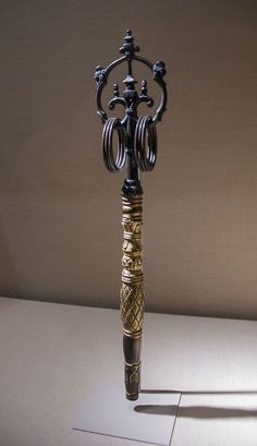 an ornate black and gold pen on a white surface with the light shining through it