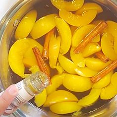 a person is holding a bottle in a bowl full of yellow peppers and carrots