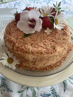 a cake with strawberries and white flowers on it sitting on a glass platter