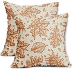 two orange and white decorative pillows on a white background, one with an oak leaf pattern