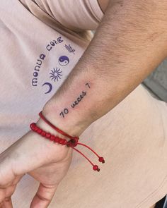 a man with a tattoo on his arm is sitting down and holding onto a red string