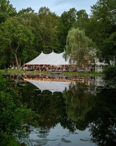 a tent is set up by the water for an outdoor party