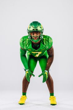 a football player in green and yellow is posing for the camera with his helmet on