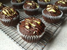 chocolate cupcakes with white and yellow frosting on a cooling rack