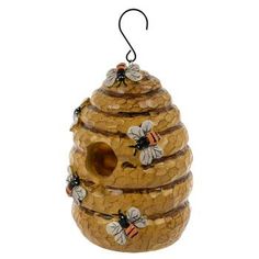 a wooden beehive hanging from a hook on a white background with three bees in it