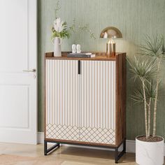 a white and brown cabinet next to a potted plant