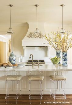 an open kitchen with white cabinets and gold pendant lights hanging from the ceiling over the island