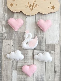 a wooden sign with pink and white felt hearts hanging from it's sides on a wood background