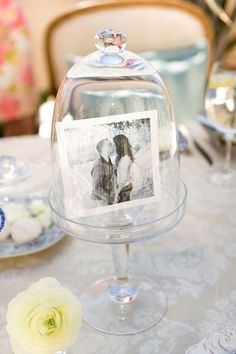 a table topped with a cake covered in frosting and a glass clochet