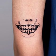 a tattoo on the arm of a person with teeth and pencils in their mouths