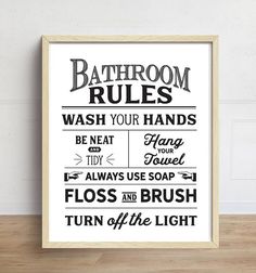 a bathroom rules poster hanging on the wall above a wooden floor with a white frame