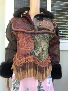 This vintage J Wilde brocade 'Jungle' jacket is a great find for the vintage and wearable art enthusiast. Any bohemian admirer or hippie fashion lover will be thrilled at this fusion of a stunning multicoloured design with fringe accents, faux fur, corded braid, and wool tweed. As well as being a visual feast of mixed media, it's warm and comfortable for the cooler months ahead. The jacket is in pre-owned condition, but its hard to see any signs of wear on this jacket. It's got big shoulders, fu Vintage Brown Patchwork Outerwear, Vintage Fall Costume Outerwear, Vintage Multicolor Outerwear For Festival, Vintage Reworked Winter Outerwear, Vintage Reworked Outerwear For Winter, Bohemian Winter Costume Outerwear, Steampunk Fitted Outerwear For Festivals, Brown Costume Outerwear With Buttons, Vintage Multicolor Outerwear With Buttons