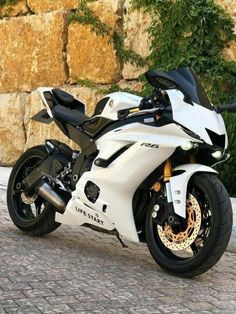 a white and black motorcycle parked next to a stone wall