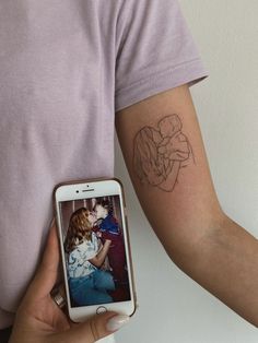 a person holding a cell phone with a tattoo on their arm