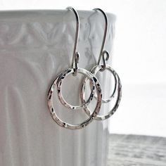 "Sterling Silver Earrings, Hammered Circle Earrings, Hammered Hoop Earrings, Argentium Sterling Silver, Modern jewelry, Silver Dangle Earring Hammered Circles made from fusing argentium sterling silver wire dangle from hand formed ear wires in these simple, classic earrings. All materials are tarnish resistant Argentium sterling silver. Ear wires are hammered rings are tumbled for superb shine and durability. Total length from top curve of earwire: 1 1/4\" (3.3cm) Diameter of largest ring: 5/8\" Modern Jewelry Silver, Jordan Earrings, Pmc Earrings, Silver Jewelry Handmade Earrings, Silver Hammered Ring, Silversmithing Jewelry, Rectangular Earrings, Silver Clay, Hammered Silver Ring