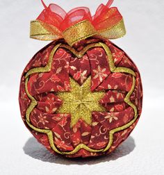 a red ornament with a gold star on it's side and a bow