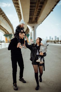 a woman holding a baby while standing next to a man