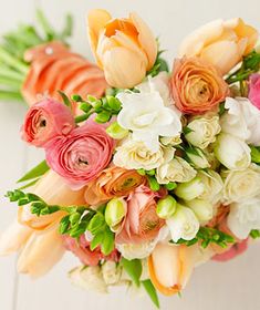 a bridal bouquet with orange and pink flowers on a white tableclothed surface