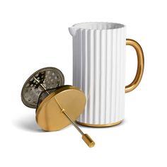 a white coffee cup with a gold handle next to a clock on the inside of it