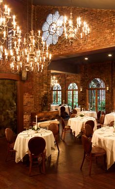 a dining room with tables and chandeliers hanging from the ceiling, surrounded by windows