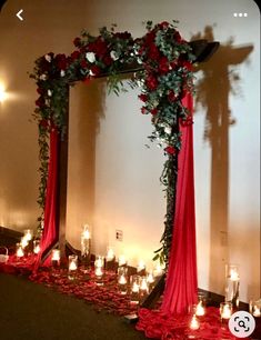 a red and white wedding arch with candles