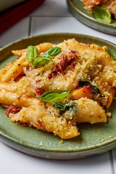 two plates filled with pasta and vegetables on top of a white tablecloth covered table