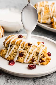 cranberry scones with icing on a white plate next to a fork