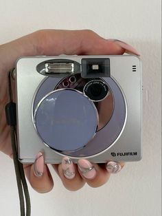 a woman holding a camera with her hands and nails on top of the camera lens