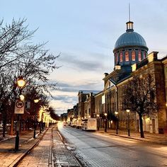 an empty city street at dusk with snow on the ground and buildings in the background