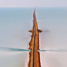 an aerial view of a long road in the middle of the ocean with cars driving on it