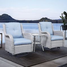 two white wicker chairs sitting next to each other on a patio with water in the background