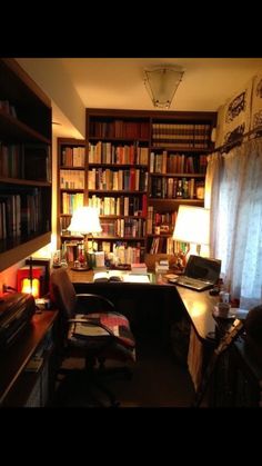 a room with a desk, bookshelf and lamp in the corner is lit by two lamps