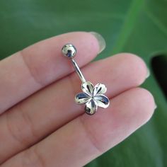 a person is holding a flower shaped nose ring in their left hand and there is a green leaf behind it