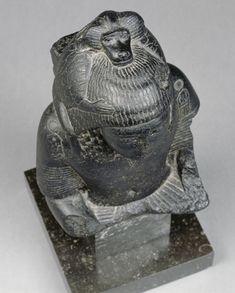 an ancient statue of a seated buddha on a black marble base, possibly in the early 20th century