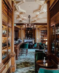 the interior of a fancy restaurant with green chairs and wooden paneled walls on either side