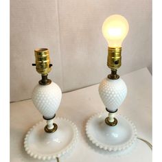 two white and gold table lamps sitting on top of each other