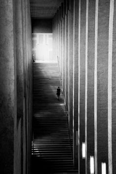 a person is walking down the stairs in an empty building with light coming from behind