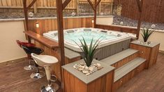 a hot tub sitting on top of a wooden deck next to a bar and chairs